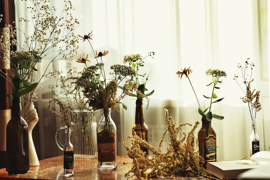 Selection of hand cut and wild flowers positioned in make shift vessels such as old glass bottles