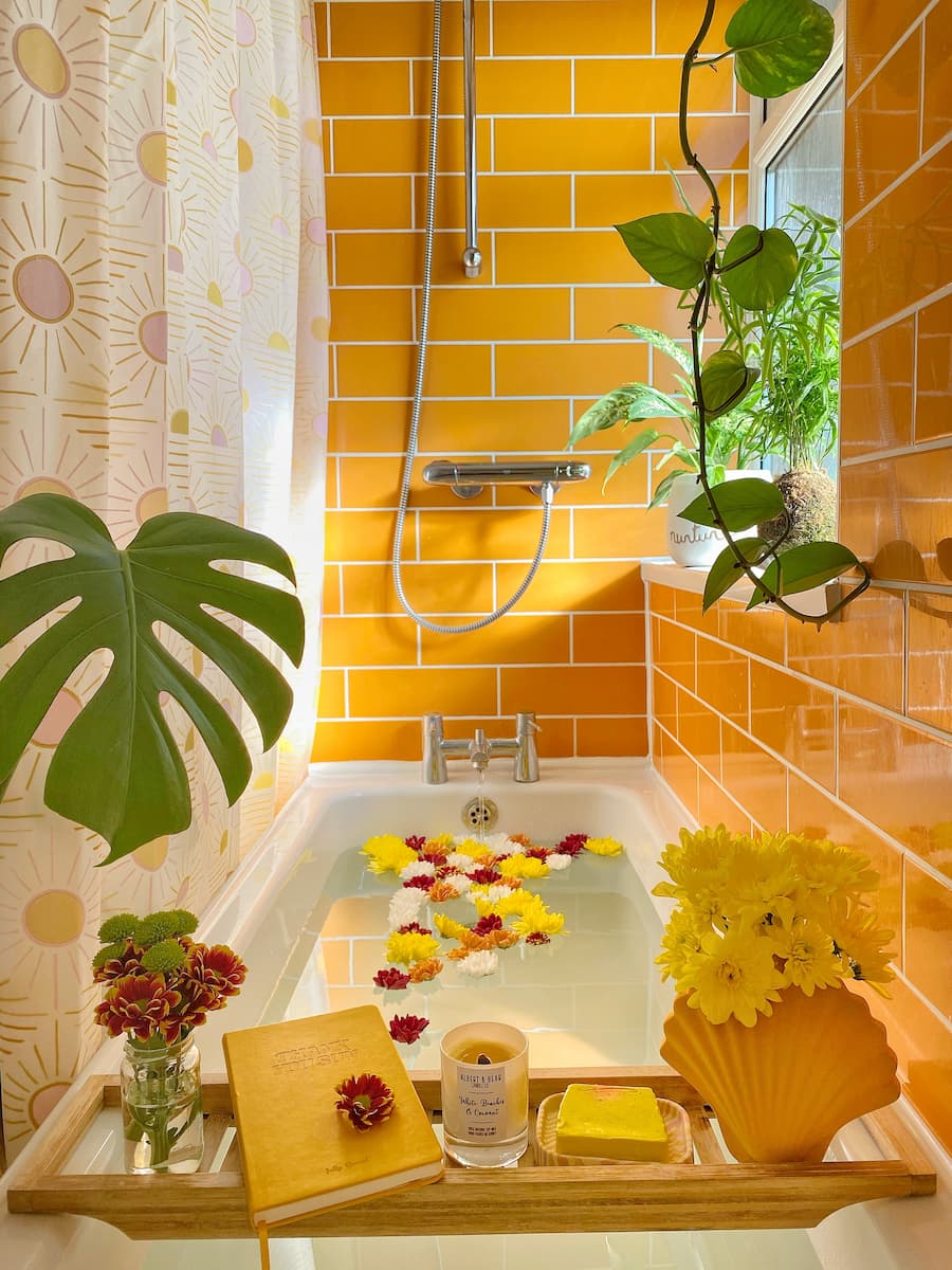 Bright yellow tiled bathroom, styled with flower petals in the bath