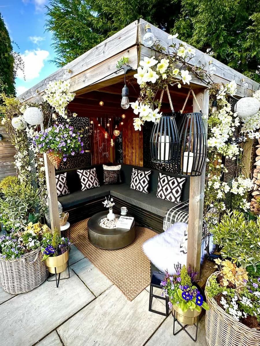 Stunning pergola which has been styled with lanterns, flowers and cushions are arranged on the corner sofa
