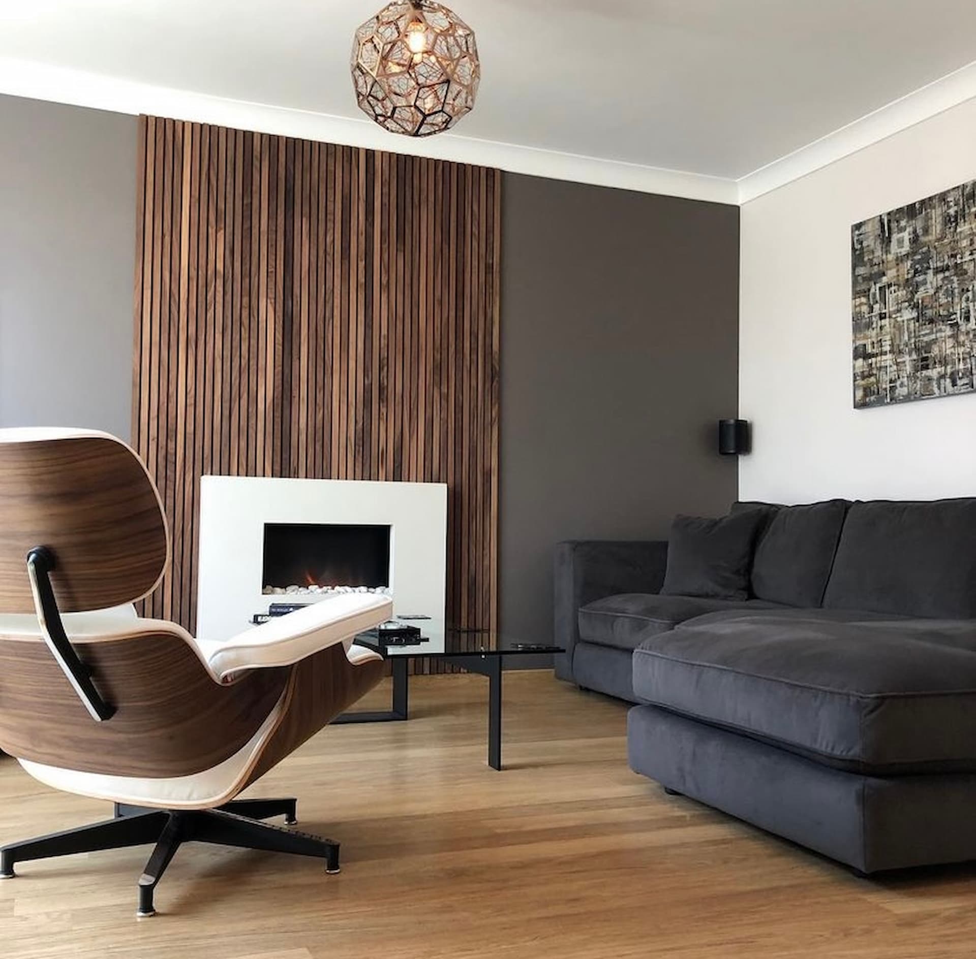 Warm earthy living room, with a dark brown feature wall with wood panelling in the centre of the wall made from American walnut