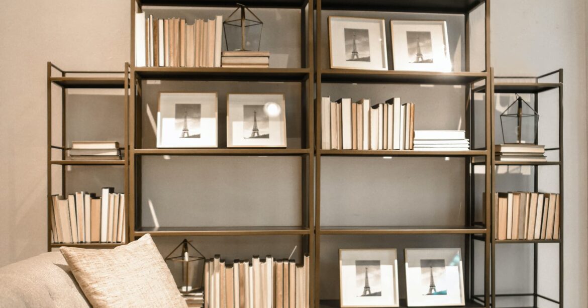 Brass coloured shelving unit displayed with books and photos in a very minimalist style