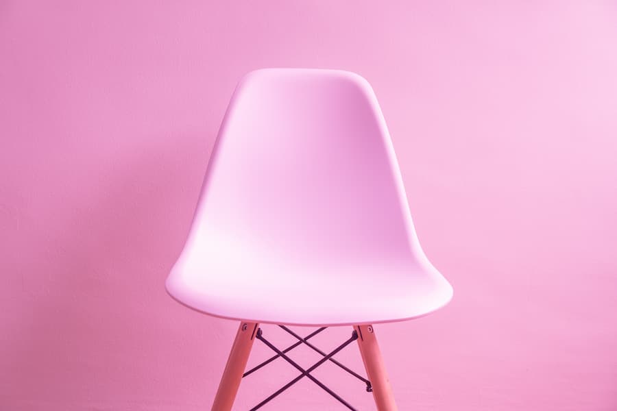 Pale pink plastic chair up against a brighter pink painted wall