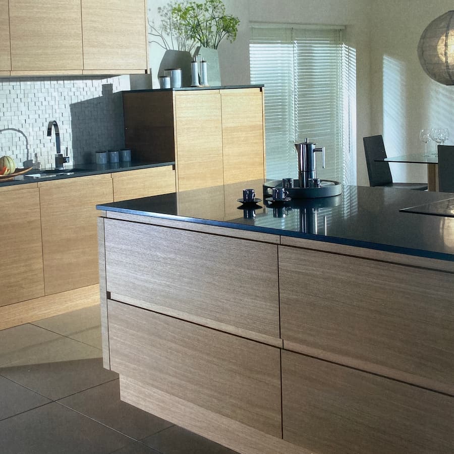 Modern kitchen design with an island in a walnut colour and oak units in the background