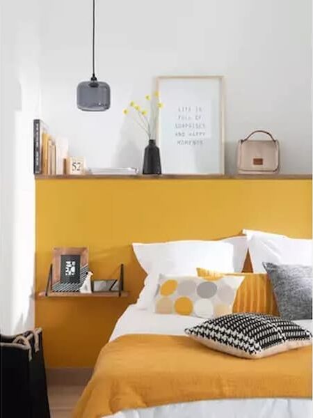 boxed in area behind the bed painted in yellow which doubles up as a headboard and shelving unit