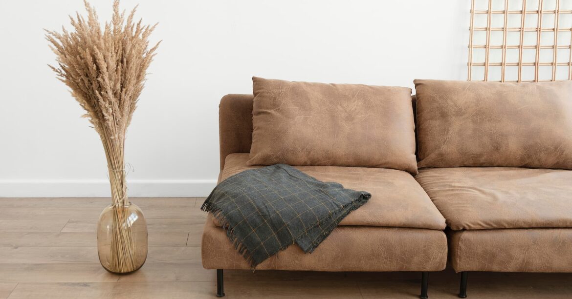 minimalist living room with brown sofa and a vase with pampas grass to the left
