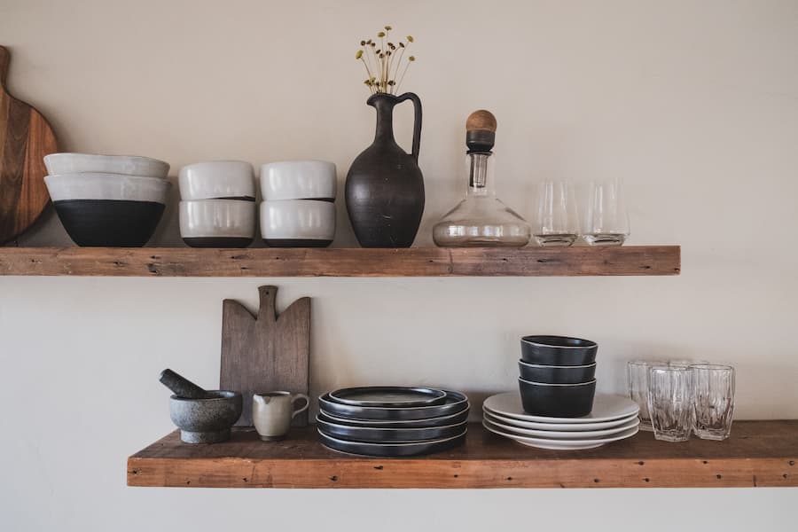 two dark wooden shelves with kitchen accessories styled on them