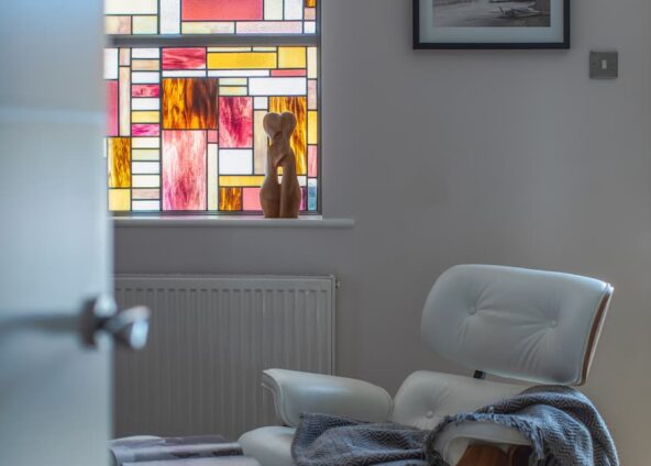 home transformation with adding a stained glass window in the living room with white Charles Eames chair positioned in front